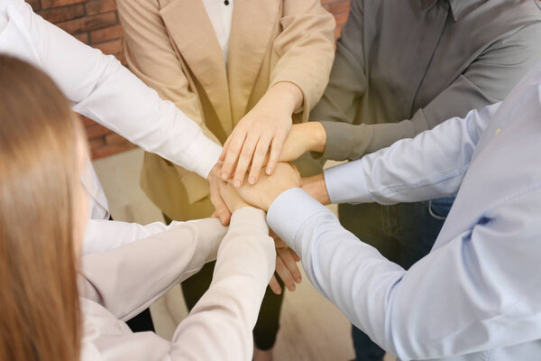 Group of volunteers putting their hands together indoors, closeup