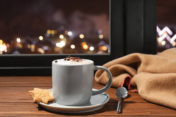 Composition with cup of hot winter drink on windowsill against blurred lights — Stock Photo, Image