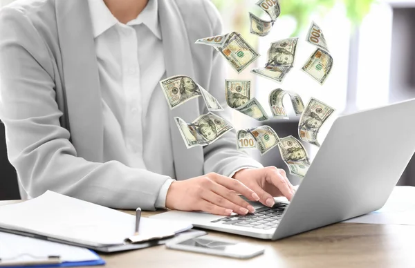 Женщина с современным ноутбуком и банкнотами за столом в офисе, крупным планом. Люди зарабатывают деньги в интернете — стоковое фото