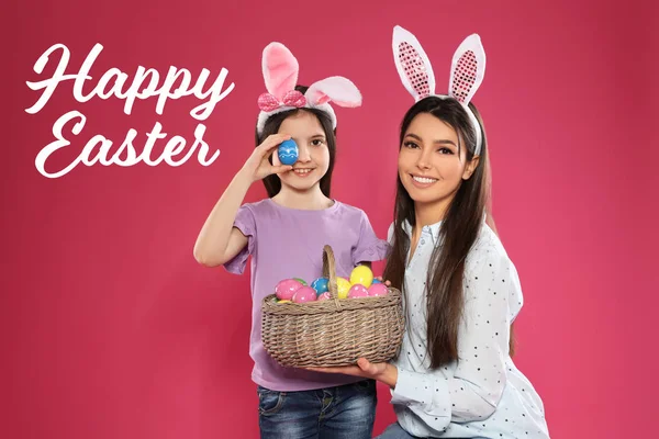 Madre e hija en diademas de orejas de conejo con huevos sobre fondo de color. Feliz Pascua — Foto de Stock
