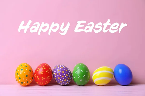 Festett tojások fából készült asztal és szöveg boldog Húsvét színes háttérrel — Stock Fotó