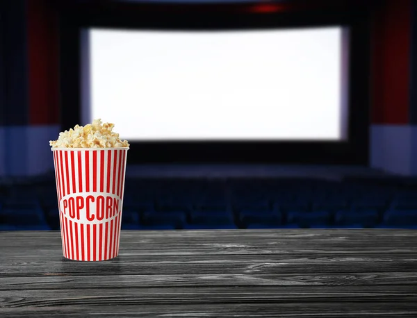 Copa de palomitas de maíz sobre mesa de madera en sala de cine vacía. Espacio para texto — Foto de Stock