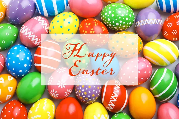 Many colorful painted eggs and text Happy Easter, top view — Stock Photo, Image