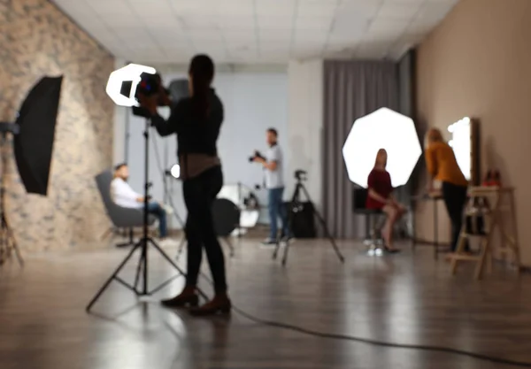 Estudio fotográfico borroso con equipo profesional y equipo de trabajadores — Foto de Stock