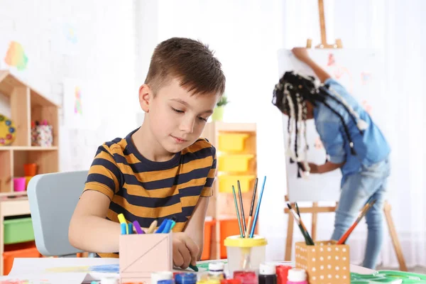 Cute little child drawing at painting lesson indoors — Stock Photo, Image