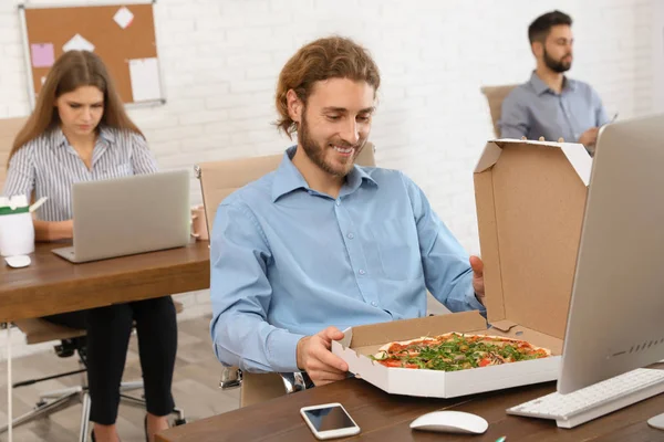 Empleado de oficina comiendo pizza en el lugar de trabajo. Entrega de alimentos — Foto de Stock