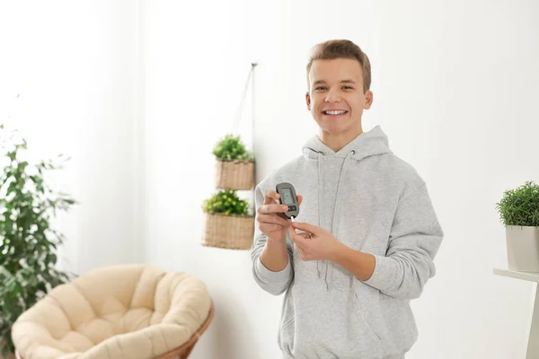 Adolescente segurando glicosímetro digital em casa. Controlo da diabetes — Fotografia de Stock