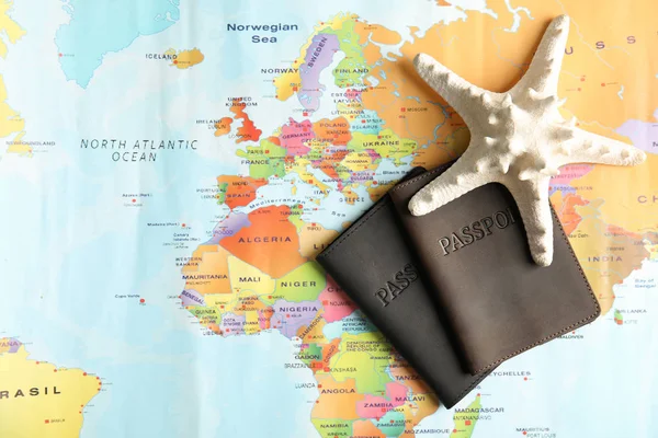 Paszporty i rozgwiazdy na mapie świata, widok z góry. Biuro podróży — Zdjęcie stockowe