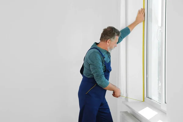 Service man measuring window for installation indoors. Space for text