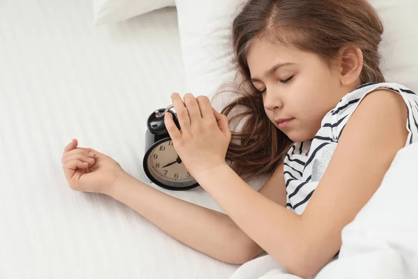 Roztomilá holčička s budíkem spí v posteli, nad zobrazením — Stock fotografie