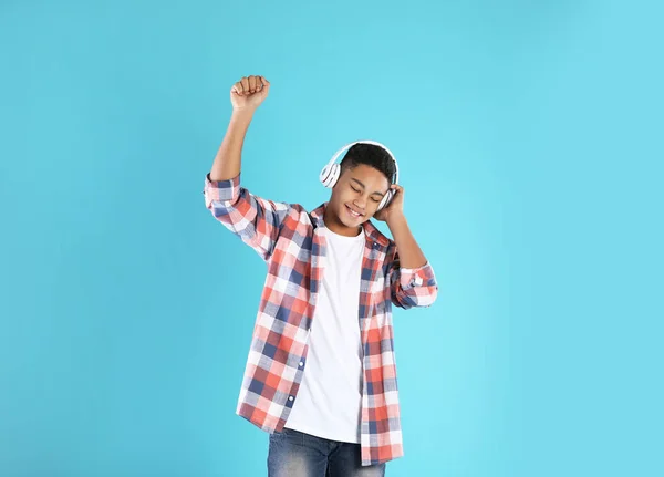 Adolescent afro-américain écoutant de la musique avec écouteurs sur fond de couleur — Photo