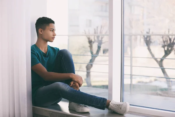 Aufgebrachter afrikanisch-amerikanischer Teenager sitzt allein am Fenster — Stockfoto