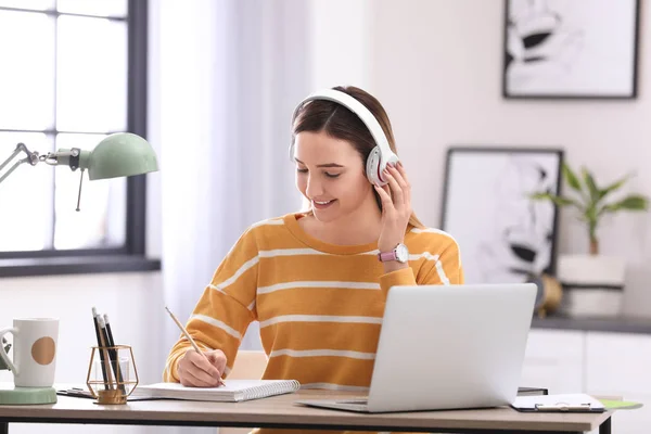 10 代の少女が彼女の部屋で宿題をしながら音楽を聴く — ストック写真