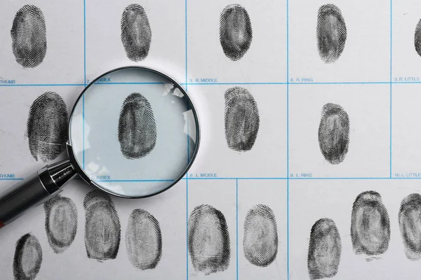 Lente d'ingrandimento e carta di impronte digitali criminali, vista dall'alto — Foto Stock