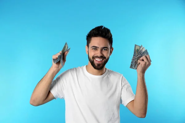 Porträt eines glücklichen jungen Mannes mit Geld auf farbigem Hintergrund — Stockfoto