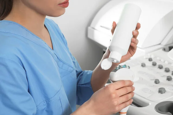 Sonographer covering ultrasound machine probe with gel in clinic, closeup — Stock Photo, Image
