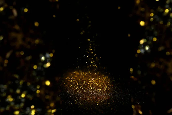 Spruzzando brillantini d'oro su sfondo nero, effetto bokeh — Foto Stock
