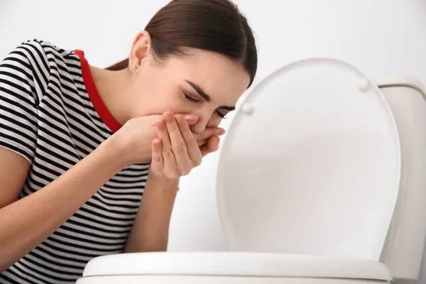 Mulher jovem que sofre de náusea em vaso sanitário dentro de casa — Fotografia de Stock