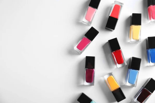 Bottles of bright nail polish on white background, top view — Stock Photo, Image