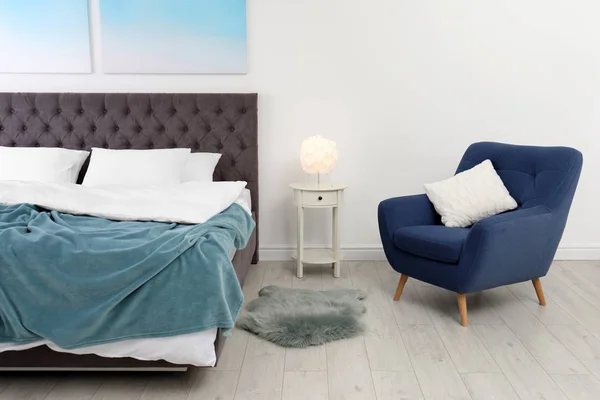 Стильный интерьер с удобной двуспальной кроватью и креслом — стоковое фото