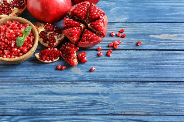 Mangkuk dengan biji dan buah delima matang pada latar belakang kayu, top view. Ruang untuk teks — Stok Foto