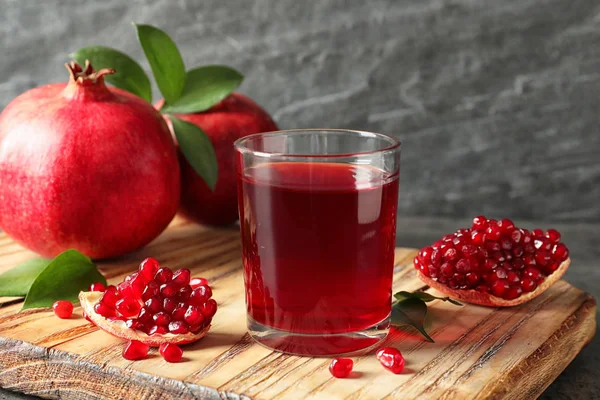 Bicchiere di succo di melograno e frutta fresca su tavola di legno su sfondo grigio — Foto Stock