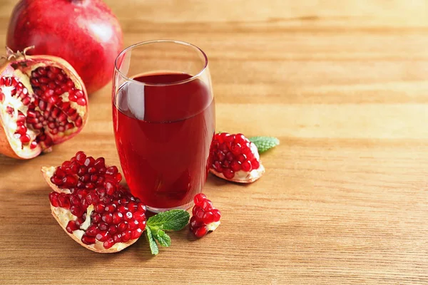 Gelas jus delima dan buah-buahan segar di latar belakang kayu, ruang untuk teks — Stok Foto