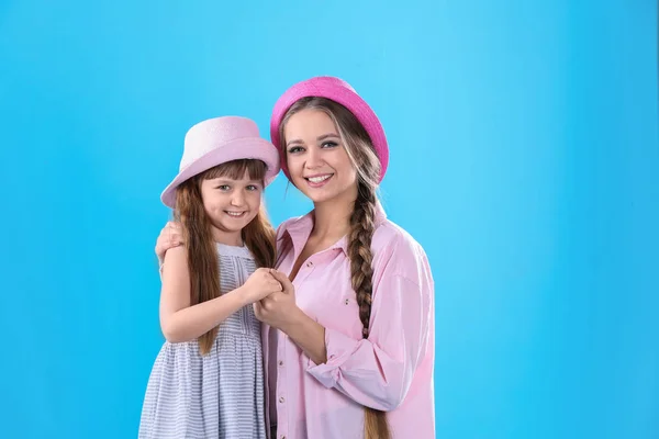 Glückliche Frau und Tochter in stilvoller Kleidung auf farbigem Hintergrund — Stockfoto