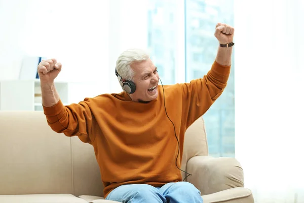 Portrait of mature man with headphones on sofa indoors — Stock Photo, Image