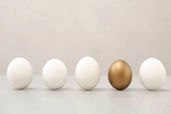 Złote jajo, między innymi, na jasnym tle — Zdjęcie stockowe