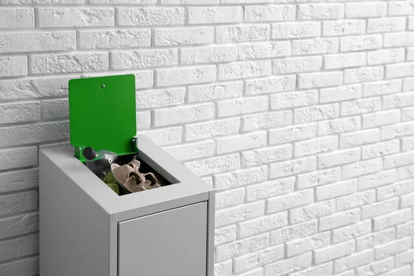 Overfilled trash bin near brick wall, space for text. Recycling concept — Stock Photo, Image