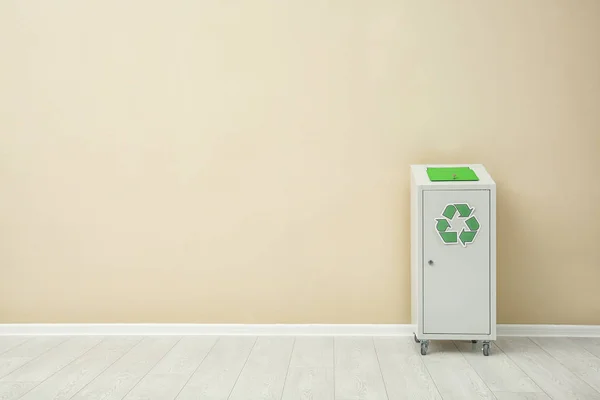 Prullenbak met recycling symbool in de buurt van kleur muur binnenshuis. Ruimte voor tekst — Stockfoto