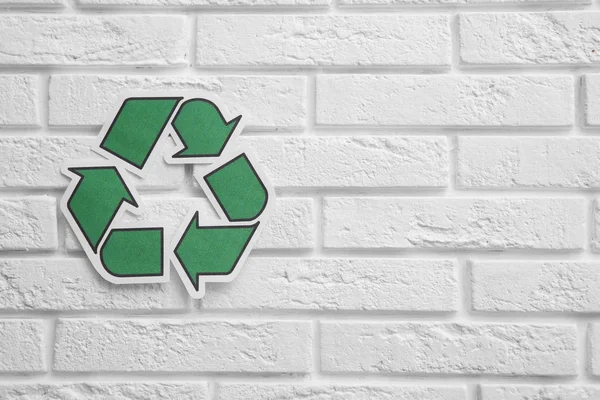 Paper recycling symbol on brick wall. Space for text