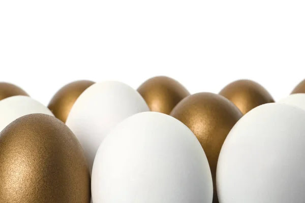 Huevos dorados entre otros sobre fondo blanco — Foto de Stock