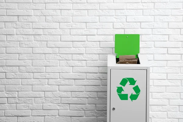 Cubo de basura sobrecargado con símbolo de reciclaje cerca de la pared de ladrillo. Espacio para texto —  Fotos de Stock