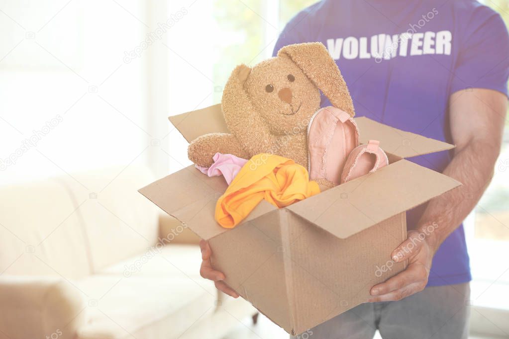 Volunteer holding box with donations indoors. Space for text