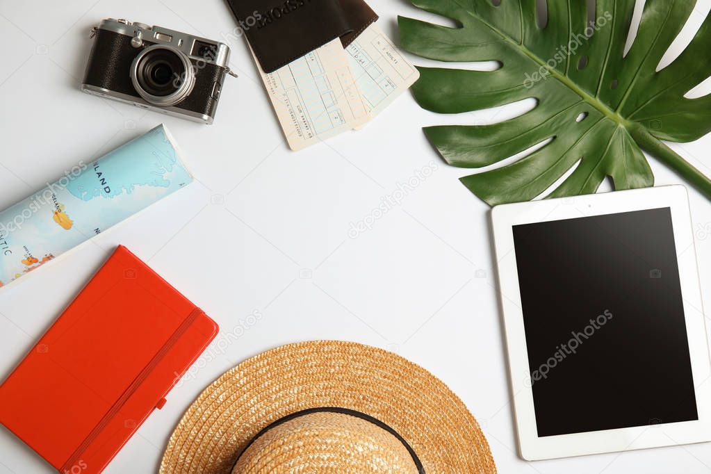 Flat lay composition with tourist items and tablet computer on white background, space for text. Travel agency