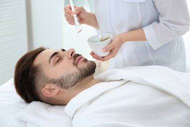 Spa salonu müşterinin yüzüne maske uygulayarak güzellik uzmanı