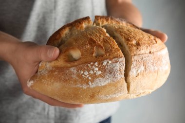 Kepekli ekmek gri arka plan üzerinde closeup tutan adam