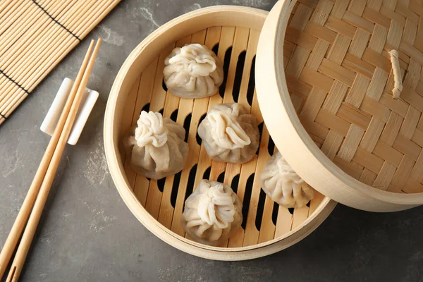Bamboo steamer with tasty baozi dumplings on table, top view