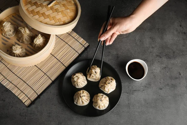 Woman eating baozi dumplings at table, top view