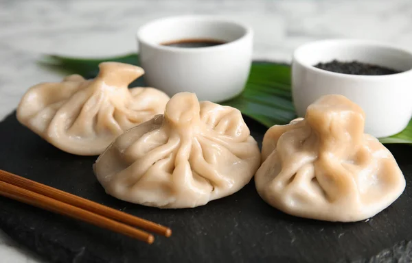 Slate plate with tasty baozi dumplings on table, closeup