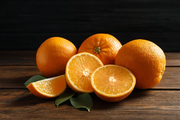 Свіжі апельсини з листям на дерев'яному столі — стокове фото