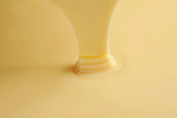 Tasty pouring condensed milk as background, closeup. Dairy product — Stock Photo, Image