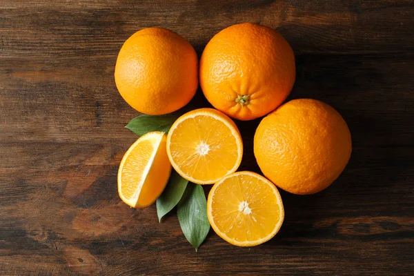 Čerstvé pomeranče s listy na dřevěné pozadí, pohled shora — Stock fotografie