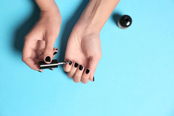 Mujer aplicando esmalte de uñas sobre fondo de color, vista superior con espacio para texto — Foto de Stock