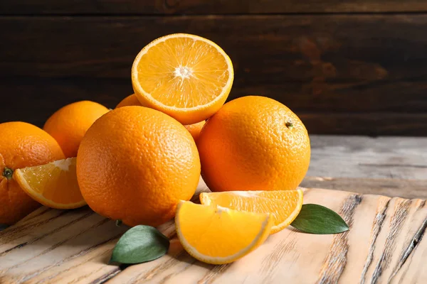 Свіжі апельсини з листям на дерев'яному столі, простір для тексту — стокове фото