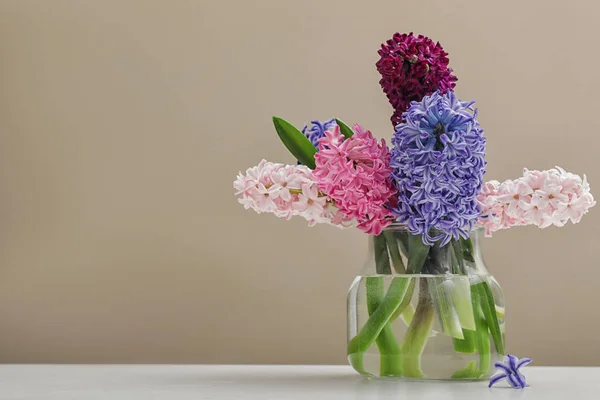 Hermosos jacintos en jarrón de vidrio en la mesa contra el fondo de color, espacio para el texto. Flores de primavera — Foto de Stock