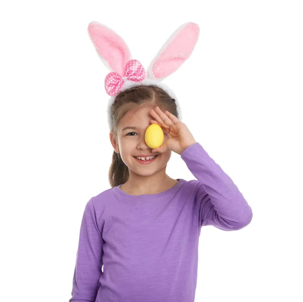 Niña en orejas de conejo diadema celebración de huevo de Pascua cerca de ojo sobre fondo blanco — Foto de Stock