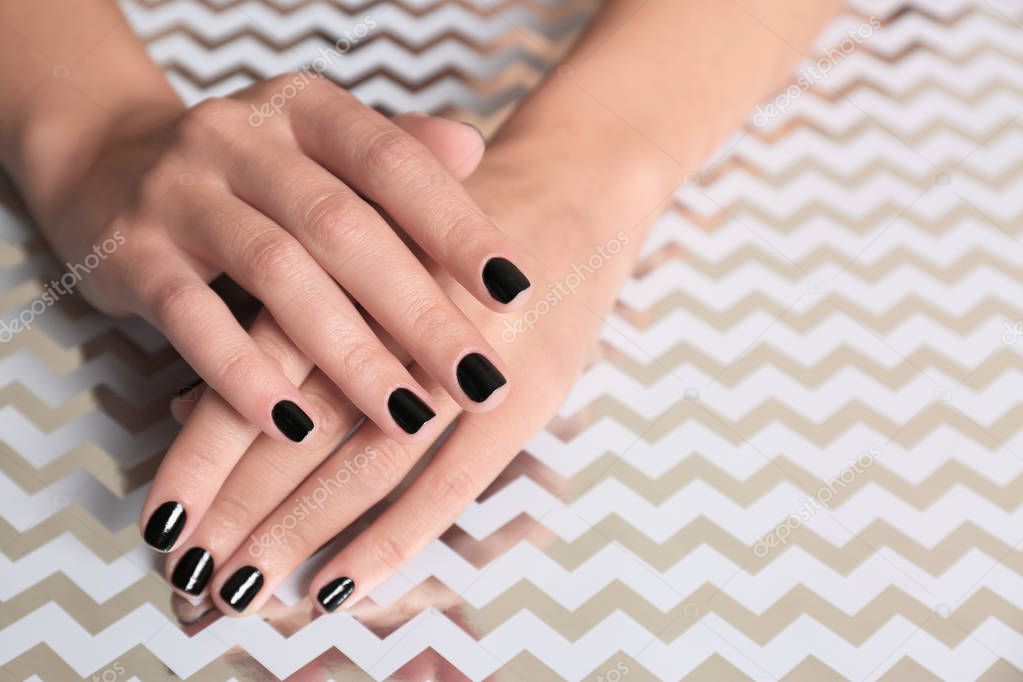 Woman showing black manicure on shining background, closeup with space for text. Nail polish trends